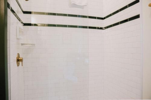 a white tiled shower with a glass door at The Woodward Hotel in Macon