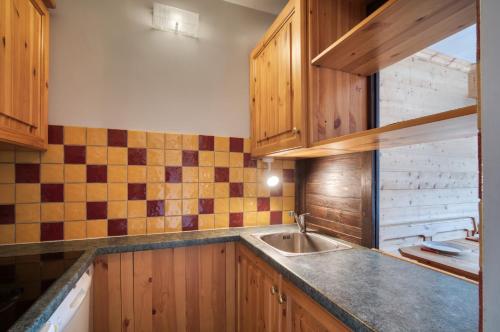 Una cocina con gabinetes de madera y un fregadero. en Appartement N° 46, en Les Menuires