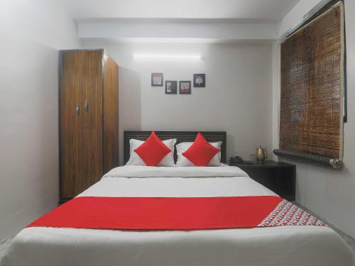 a bedroom with a large bed with red pillows at Hotel O Pillars House in Shillong