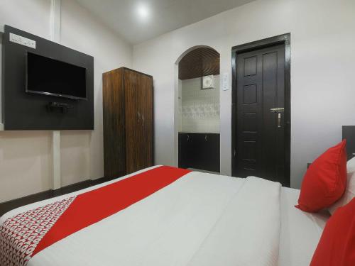 a bedroom with a bed with a television and a door at Hotel O Pillars House in Shillong