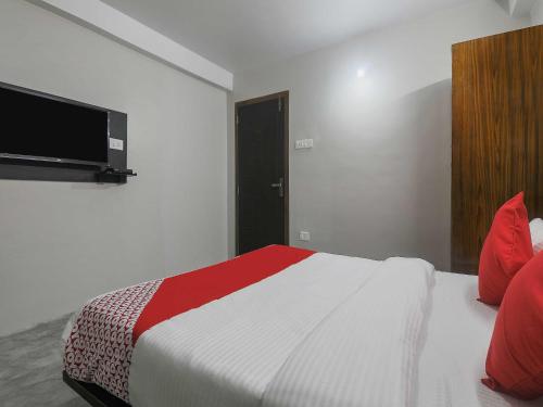a bedroom with a bed with a television on the wall at Hotel O Pillars House in Shillong