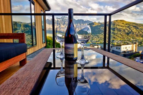 a bottle of wine and two wine glasses on a table at Mountain Lake Vista 3 Bedroom in Queenstown