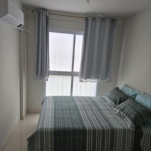 a bedroom with a bed with a plaid blanket and a window at Casa de Praia em Jacaraipe soneto do Mar in Serra