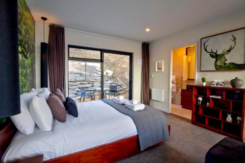 a bedroom with a large bed and a large window at Mountain Lake Vista Studio in Queenstown