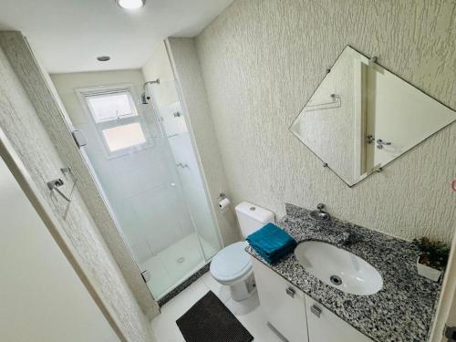 Un baño con lavabo, inodoro y espejo. en Apartamento Porto Real - Mangaratiba, en Mangaratiba