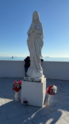 a statue of a woman sitting on a ledge with flowers at Condominio Roberta in Marinella di Sarzana