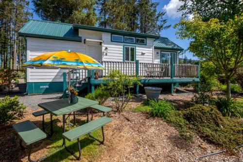 a tiny house with a picnic table and an umbrella at Sheltered Nook On Tillamook Bay in Bay City