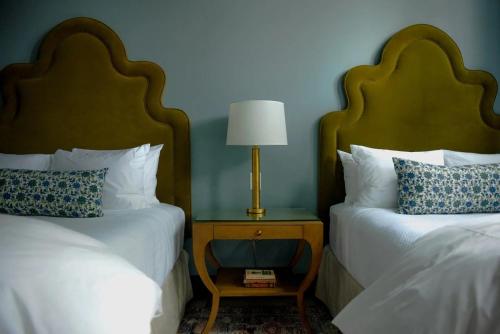 a bedroom with two beds and a table with a lamp at The Woodward Hotel in Macon