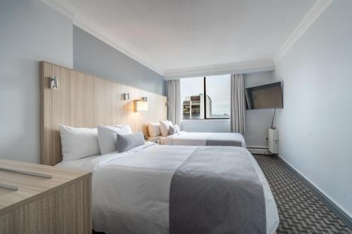 a hotel room with two beds and a television at Century Plaza Hotel in Vancouver