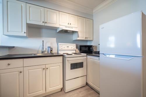 a kitchen with white cabinets and a white refrigerator at Century Plaza Hotel in Vancouver