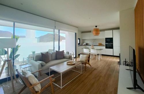 ein Wohnzimmer mit Sofa und Tisch in der Unterkunft San José Suites 3 Hab, Piscina, solárium y WiFi in Almería