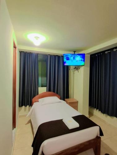 a bedroom with a bed and a flat screen tv at Kuntur House Machupicchu in Machu Picchu