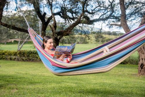 a woman laying in a hammock reading a magazine at Hacienda San Francisco in Tumbabiro