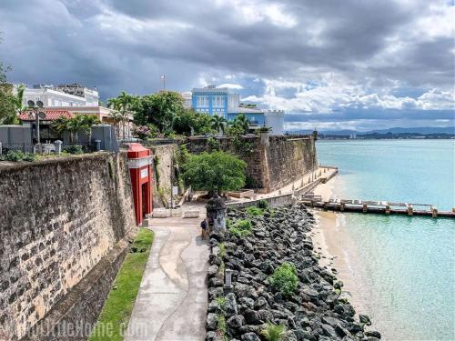 a stone wall next to a beach next to the water at Private King Room with bath in Shared Apartment in San Juan
