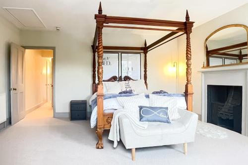 a bedroom with a canopy bed and a white chair at 3-Bed gem with Bath Abbey views in Bath