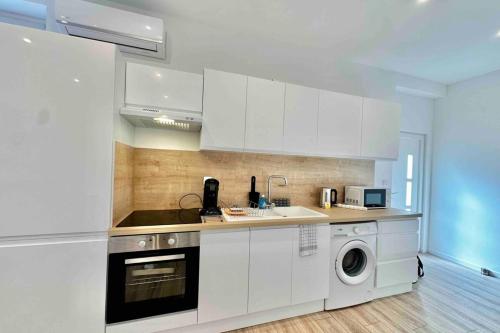 une cuisine avec des armoires blanches et une laveuse et une sécheuse dans l'établissement neuf climatisé et proche métro, à Villeurbanne