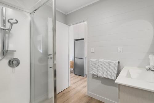 a bathroom with a shower and a sink and a mirror at Tasman Holiday Parks - Papamoa Beach in Papamoa
