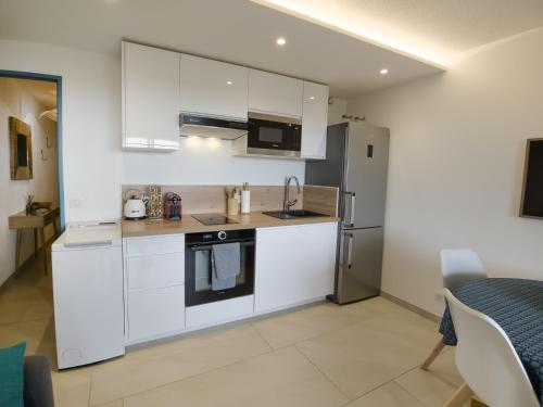 une cuisine avec des armoires blanches et un réfrigérateur en acier inoxydable dans l'établissement Superb renovated T2 beach 200m sea view terrace, à Rayol-Canadel-sur-Mer