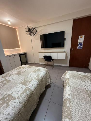 a bedroom with two beds and a flat screen tv at Hotel Gboss in Punta Hermosa
