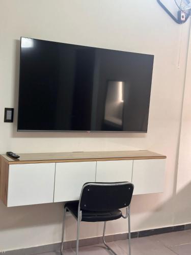 a tv on a wall with a black chair at Hotel Gboss in Punta Hermosa