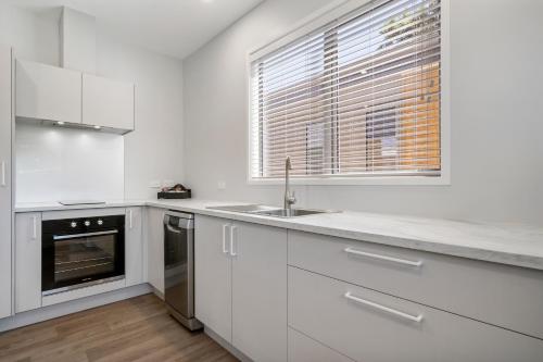 a kitchen with white cabinets and a sink and a window at Tasman Holiday Parks - Papamoa Beach in Papamoa