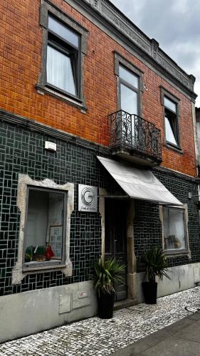 a brick building with a balcony and a window at Feel at Home Guest House in Ovar