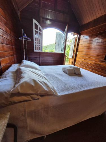 a large bed in a room with a window at Pássaro de Fogo in Santo Antônio do Pinhal