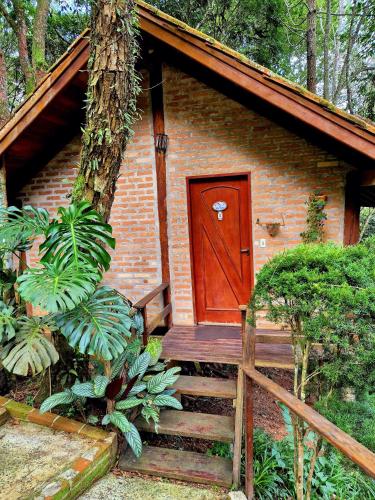 a small brick house with a red door and stairs at Pássaro de Fogo in Santo Antônio do Pinhal