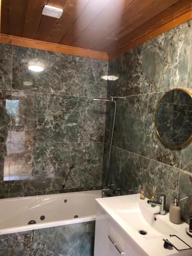 a bathroom with a tub and a sink and a mirror at Casa das Fragas in Celorico de Basto