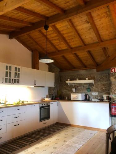 a kitchen with white cabinets and a wooden ceiling at Casa das Fragas in Celorico de Basto