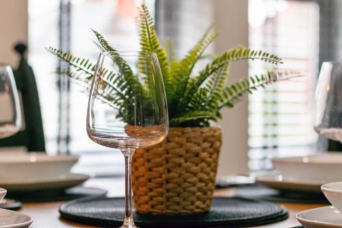 a table with a vase with a plant and a wine glass at 3a Roman View, beautifully appointed apartment in Roundhay, sleeps up to 6, bedrooms with en suite bathrooms, EV charging in Moortown