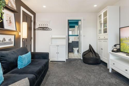 a living room with a black couch and a tv at 3a Roman View, beautifully appointed apartment in Roundhay, sleeps up to 6, bedrooms with en suite bathrooms, EV charging in Moortown
