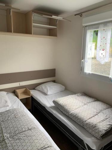 deux lits dans une petite pièce avec une fenêtre dans l'établissement Camping de Bourg Charente, à Bourg-Charente