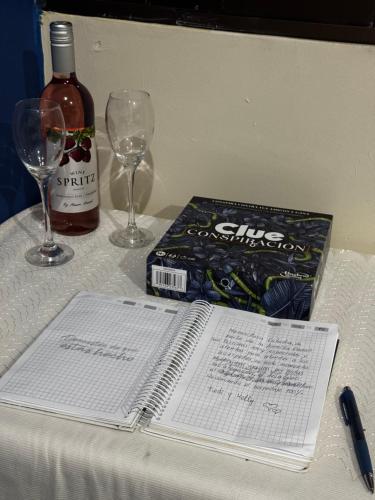 a table with a bottle of wine and a book and glasses at Mini Suite en el centro de la ciudad in Macará