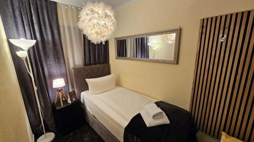 a small bedroom with a bed and a chandelier at Soho Guesthouses in Düsseldorf