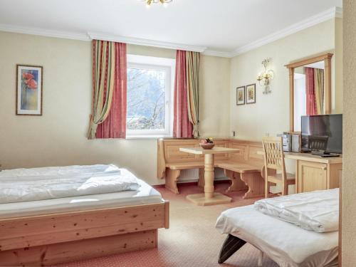 a bedroom with two beds and a desk and a table at Bergzeit Fieberbrunn 2 in Hütte