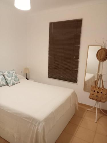 a white bedroom with a bed and a window at Piso Barbate in Barbate