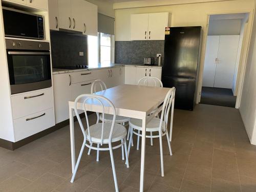 a kitchen with a table and chairs and a refrigerator at Akubra Downs, Yeppoon -Cottage 3 bedroom in Cawarral