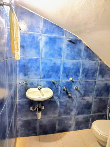 a blue tiled bathroom with a sink and a toilet at Casa Campestre - Villa Isabel in Paipa