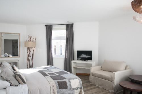a bedroom with a bed and a chair and a television at Casa Galos Hotel & Lofts in Valparaíso