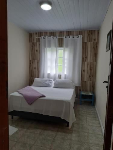 a bedroom with a white bed with a window at Casadateca in Praia Vermelha