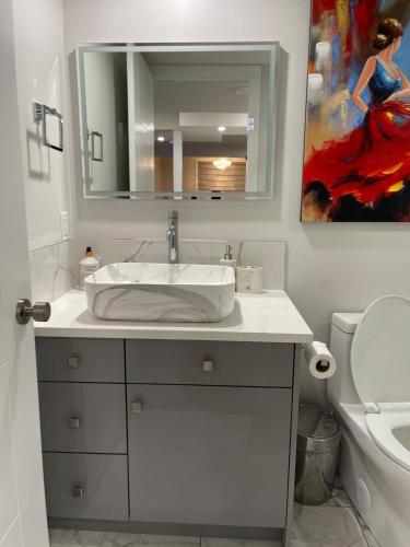 a white bathroom with a sink and a mirror at HansBnB near Airport in Calgary