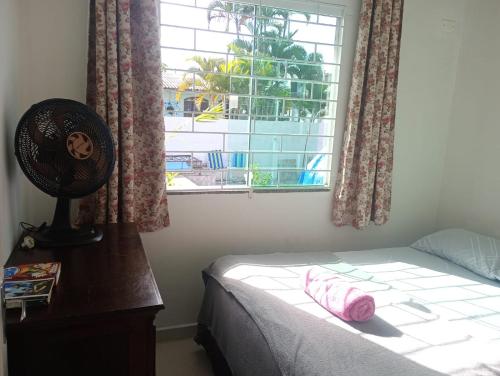 a bedroom with a bed and a window with a fan at Casa da Cegonha - Praia de Leste in Pontal do Paraná