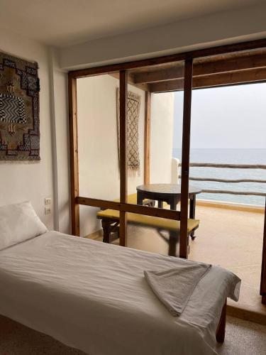 a bedroom with a bed and a view of the ocean at Taghazout beachfront Apartments in Taghazout