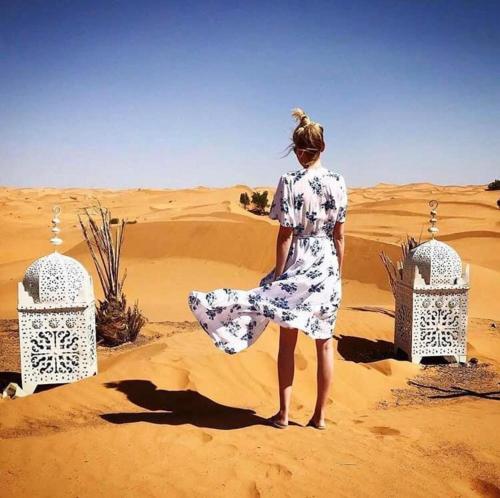 a woman in a dress standing in the desert at Aladdin merzouga camp in Merzouga