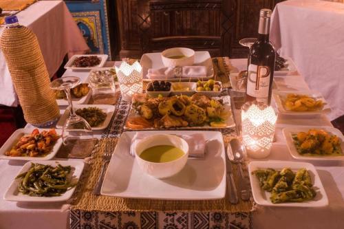 a table with plates of food and a bottle of wine at Aladdin merzouga camp in Merzouga