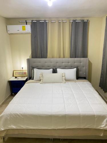 a bedroom with a large white bed with gray curtains at Luxury Apartment By Merengue House in Boca Chica