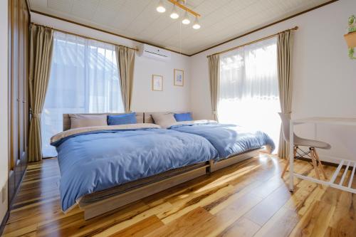 a bedroom with a large bed with blue sheets at Casa Familia Aoshima in Miyazaki