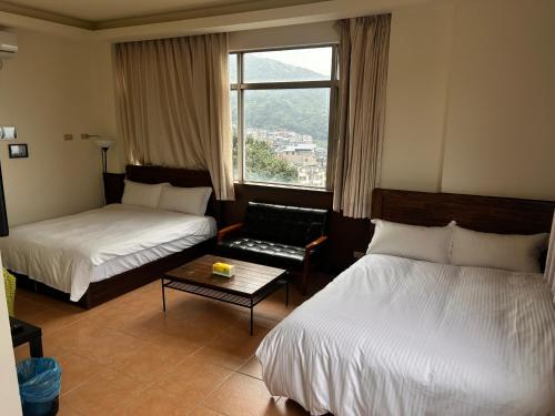 a hotel room with two beds and a window at Old Street Seaview Homestay in Jiufen