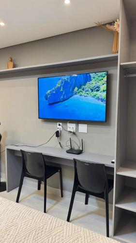 a desk with two chairs and a tv on a wall at Vert House in João Pessoa